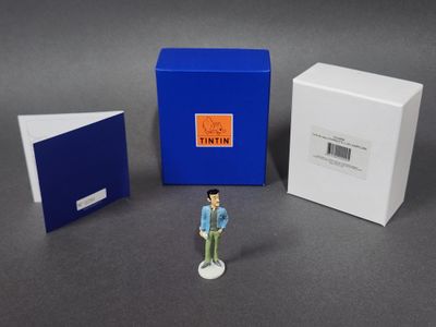 une petite figurine représentant un homme debout devant une boîte
