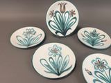four plates with flowers on them are sitting on a table
