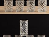 de nombreux verres posés sur une étagère avec un fond noir