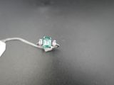 une bague en émeraude et diamants posée sur une table, avec une étiquette indiquant son prix