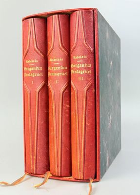 trois livres rouges dans une boîte posée sur une surface blanche