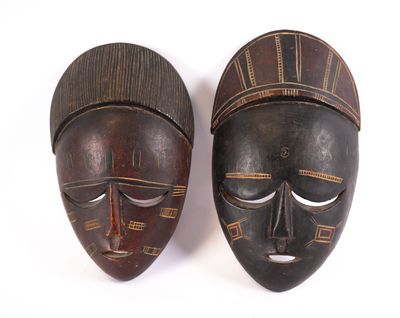 paire de masques africains sculptés en bois sur fond blanc