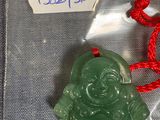 un pendentif représentant un Bouddha en jade vert, suspendu à un cordon rouge