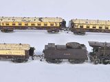 quatre petits trains miniatures posés sur une surface blanche, avec un fond blanc