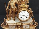a gold clock with a man and a woman on it