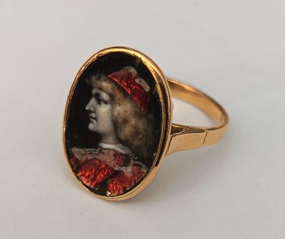 a close up of a gold ring with a picture of a woman wearing a red hat