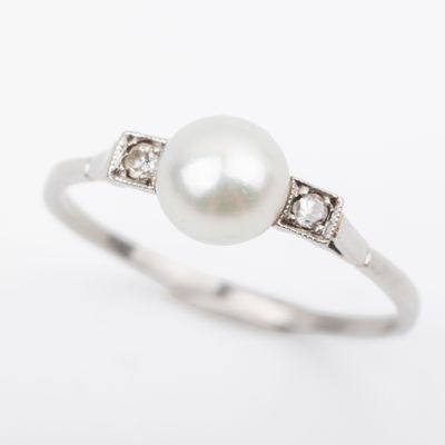 a close up of a pearl and diamond ring on a white background