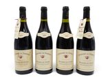quatre bouteilles de vin sont alignées sur une surface blanche