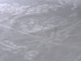 bedspread with a white floral design on it sitting on top of a wooden floor