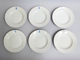 six white plates with blue writing on them sitting on a table