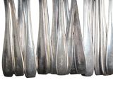 six silver spoons are lined up in a row on a white surface