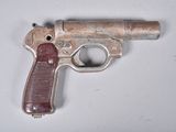 un petit pistolet jouet posé sur une surface blanche