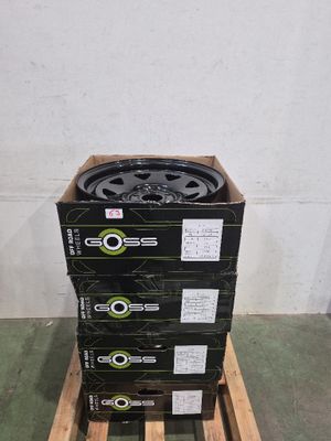 quatre cartons de pneus noirs et verts empilés sur une palette en bois