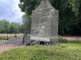 a bird cage sitting on a bench in the middle of a field