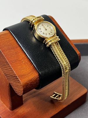 une montre posée sur un socle en bois, attachée à une chaîne en or
