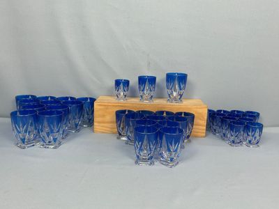 des verres à shot en verre bleu et un support en bois sur fond blanc