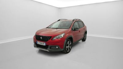 Une voiture rouge est garée dans une pièce blanche