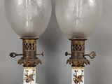 une paire de lampes en forme de vase, blanches et dorées, posées sur des socles, sur une surface grise