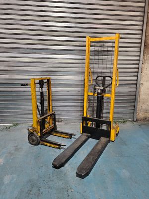 two forklifts sitting next to each other in front of a garage door
