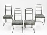 Quatre chaises en métal à l'assise rembourrée sont disposées devant un fond blanc.