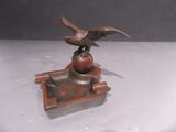 a bronze statue of an eagle sitting on top of a bowl