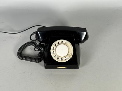 un téléphone noir posé sur une table, sur fond blanc
