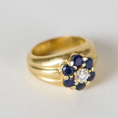 bague en or jaune sertie de saphirs bleus et de diamants sur un fond blanc