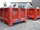 two red crates sitting next to each other on the gravel