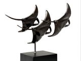trois sculptures en bronze représentant un requin, posées sur un socle noir