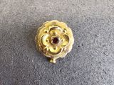 broche en forme de fleur plaquée or jaune, ornée d'un grenat au centre