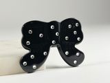 black bow broocher with silver studs sitting on a marble block