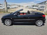 La voiture noire est garée sur le parking, près d'une clôture.
