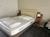 a bed with a white comforter and a green chair in the corner