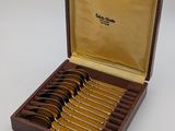 six spoons in a wooden box with a gold cover