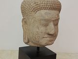 sculpture of a head of a buddha on a wooden stand