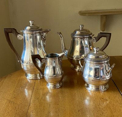 three silver coffee pots sitting on a wooden table