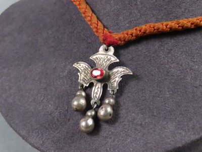 un collier sur lequel est représenté un oiseau posé sur un chapeau