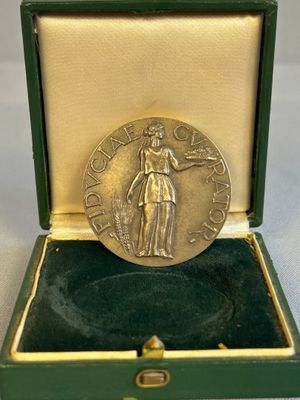 une image représentant une médaille d'or dans un coffret vert posé sur une surface blanche