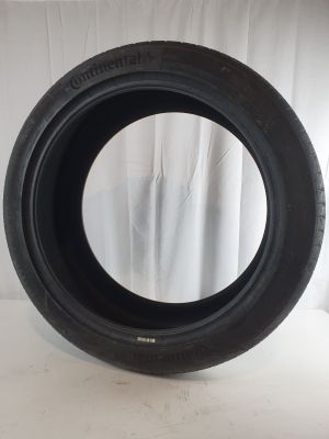a close up of a tire on a white surface with a curtain behind it