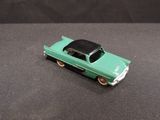 a green toy car with a black top on a black surface