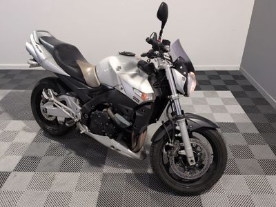 une moto argentée et noire garée sur un sol à damier