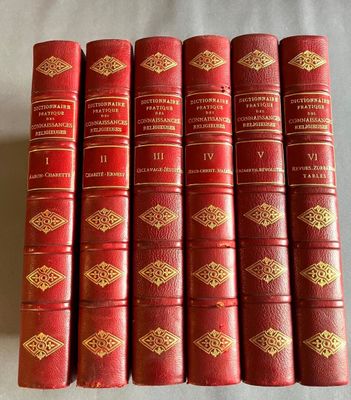 six livres en cuir rouge aux tranches dorées, posés sur un fond blanc