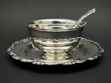 un service en argent ancien composé d'un bol et d'une cuillère posés sur une soucoupe