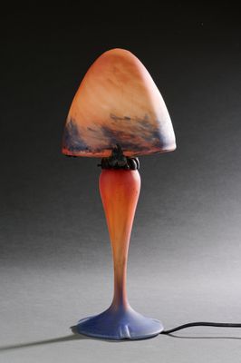 une lampe orange et bleue posée sur une table, près d'un mur noir