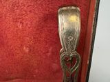a silver spoon with a heart on it sitting in a red case