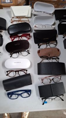 plusieurs paires de lunettes posées sur une table, à côté d'une paire de chaussures