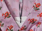 the dress is pink and has red flowers on it