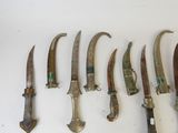 several knives are lined up on a white surface with a knife in the middle of them