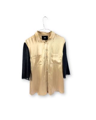 une chemise suspendue à un cintre sur un mur blanc, avec une chemise noire et dorée