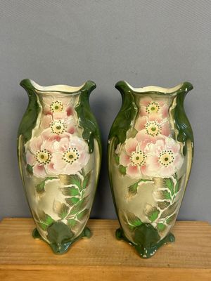 deux vases verts ornés de fleurs roses, posés sur une étagère en bois